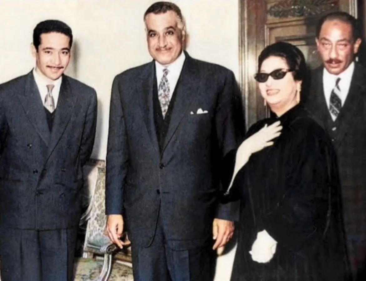 Colorized photograph of Umm Kulthum in a black dress and sunglasses standing with President Gamal Abdel Nasser, Anwar Sadat and another man.